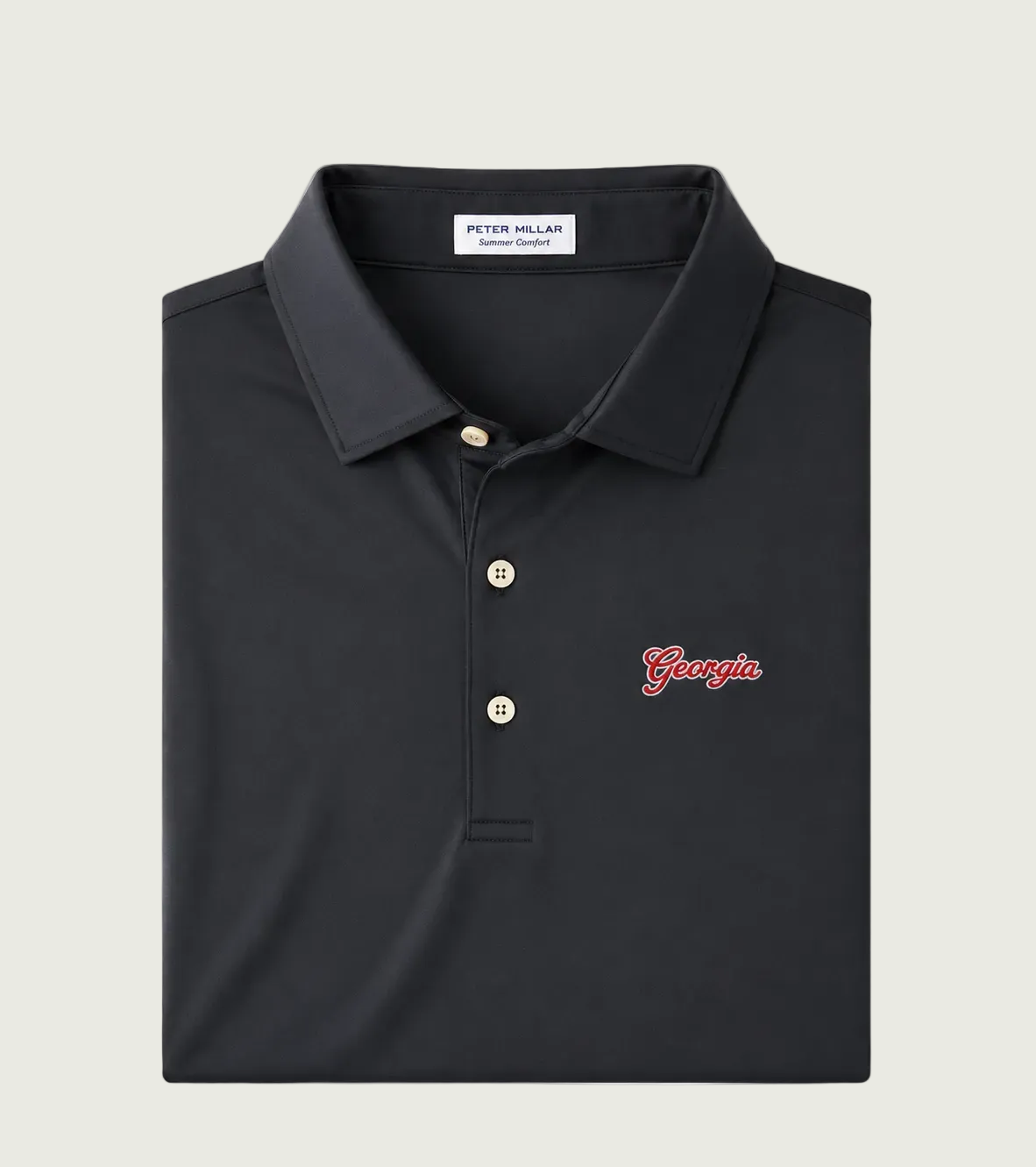 A folded Peter Millar polo shirt in black, featuring a three-button placket, a small red embroidered 'Georgia' script on the left chest, and a white neck label.