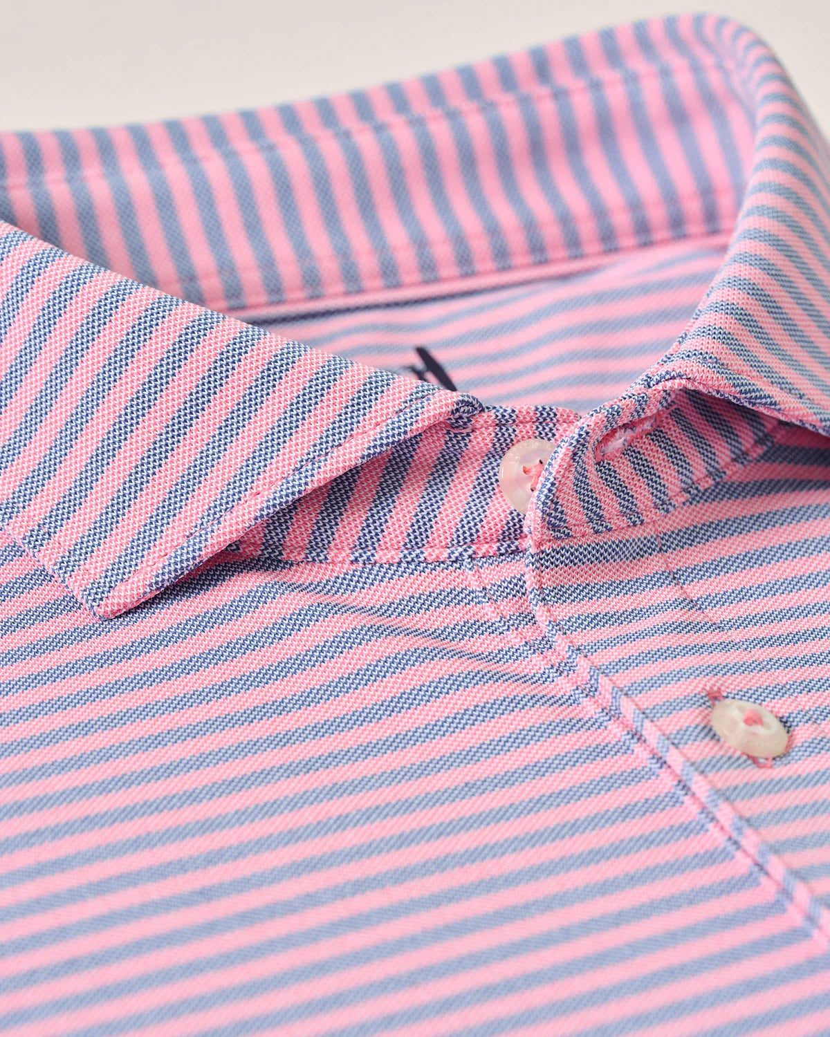 Close-up of a pink and blue striped shirt with a button detail.