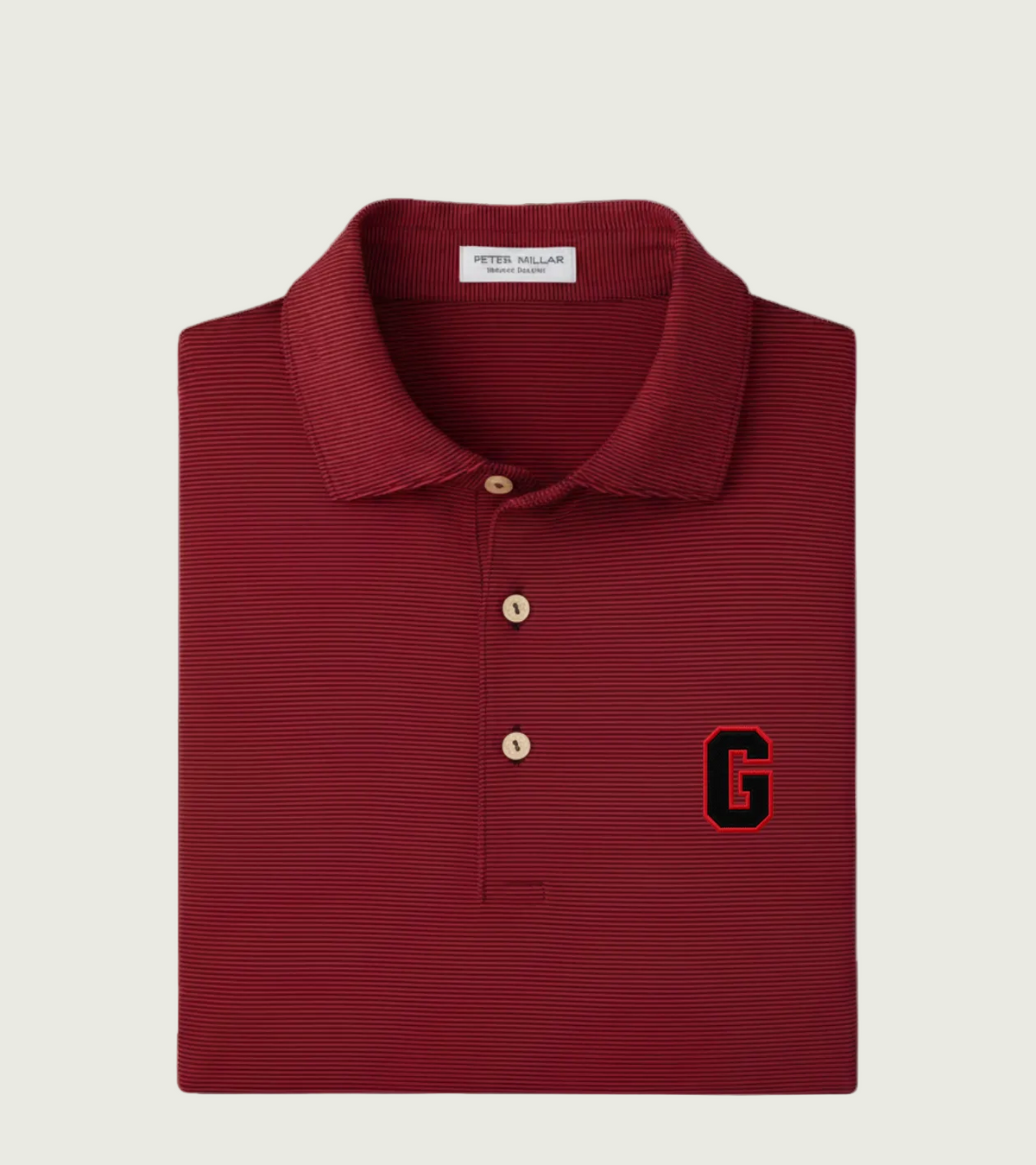 A folded Peter Millar polo shirt in a deep maroon red, featuring a textured horizontal stripe pattern, a two-button placket, and a black and red embroidered letter 'G' on the left chest.