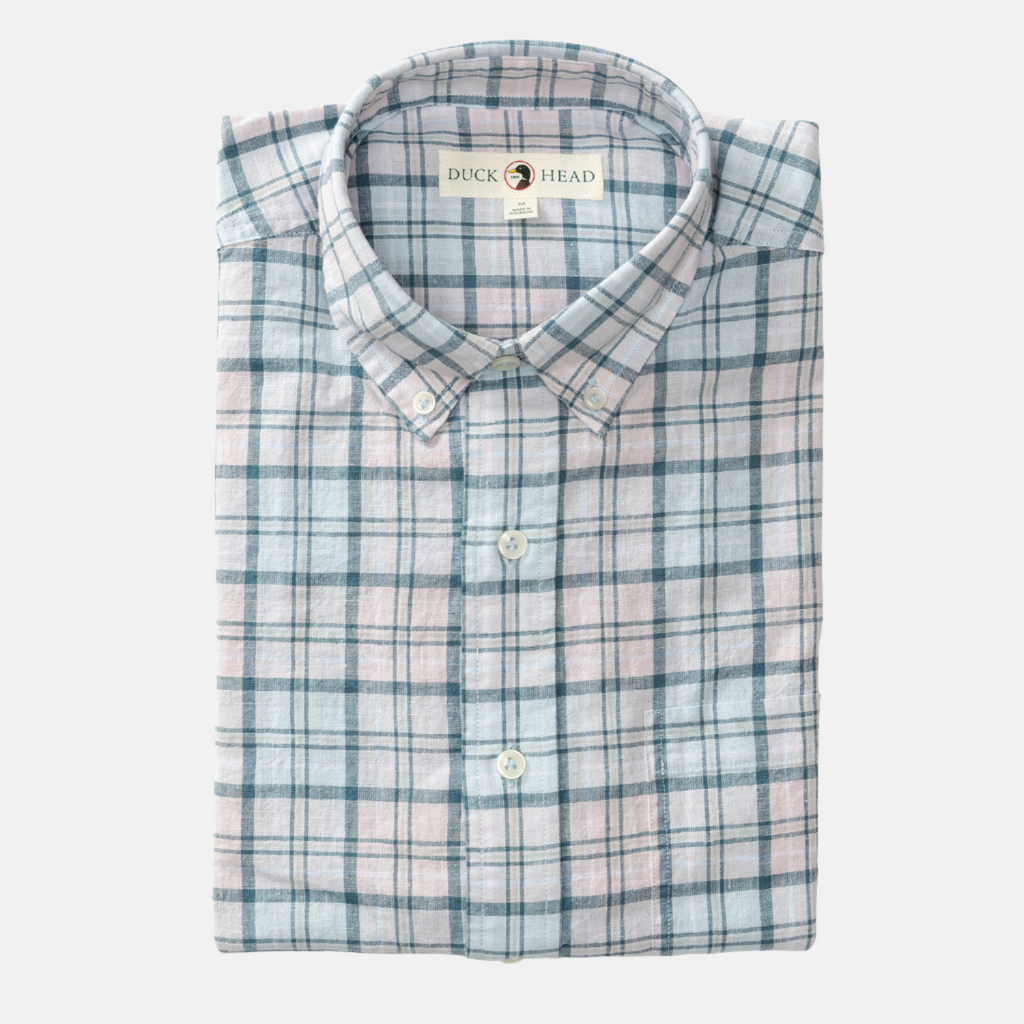 Folded Sky Blue Linen Cotton Oxford Brackett Shirt. Shirt has a sky blue background with light yellow, light pink, and dark teal plaid detailing and off-white buttons.