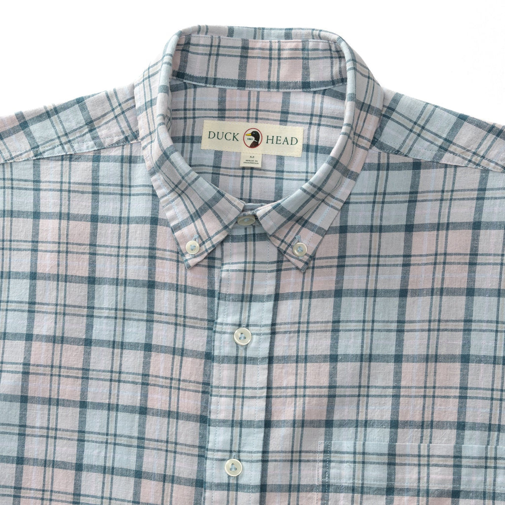 Close up of Sky Blue Linen Cotton Oxford Brackett Shirt. Shirt has a sky blue background with light yellow, light pink, and dark teal plaid detailing and off-white buttons.