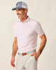 Man wearing a pink striped polo shirt, light gray cap, and beige pants on a plain background