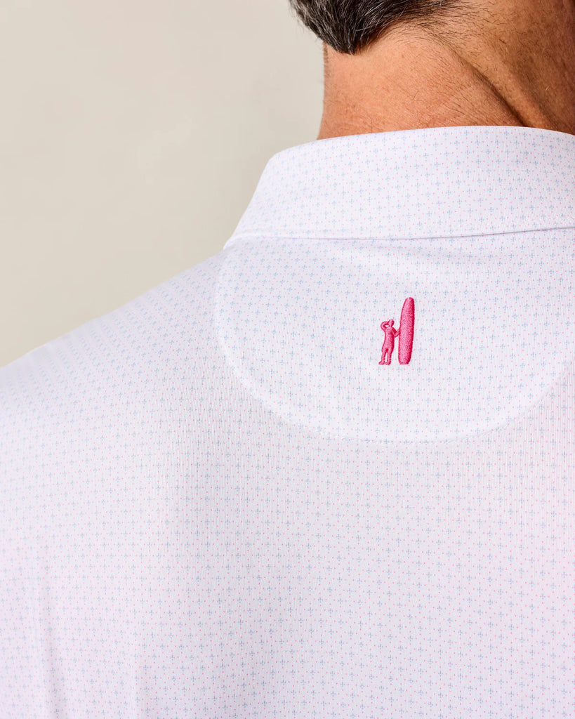Close-up of a white textured shirt with a pink logo on the collar against a beige background