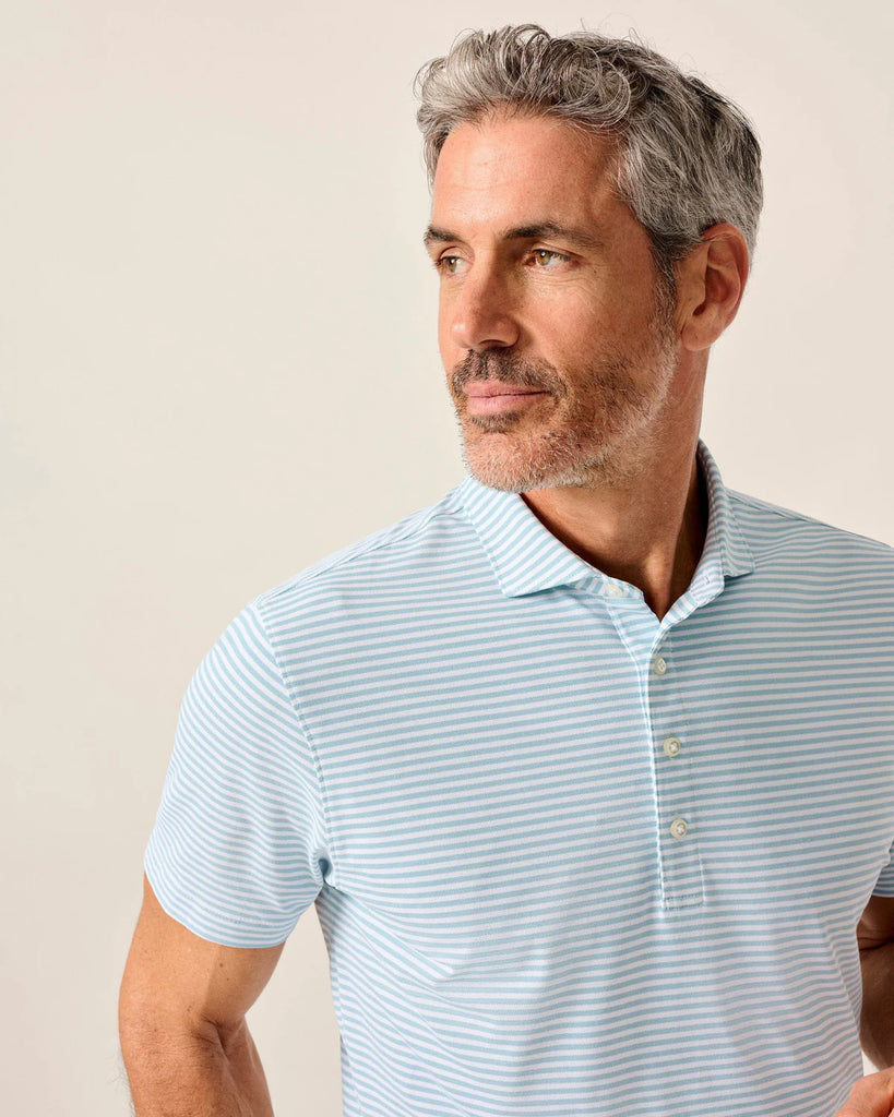 Man wearing a light blue striped polo shirt against a beige background