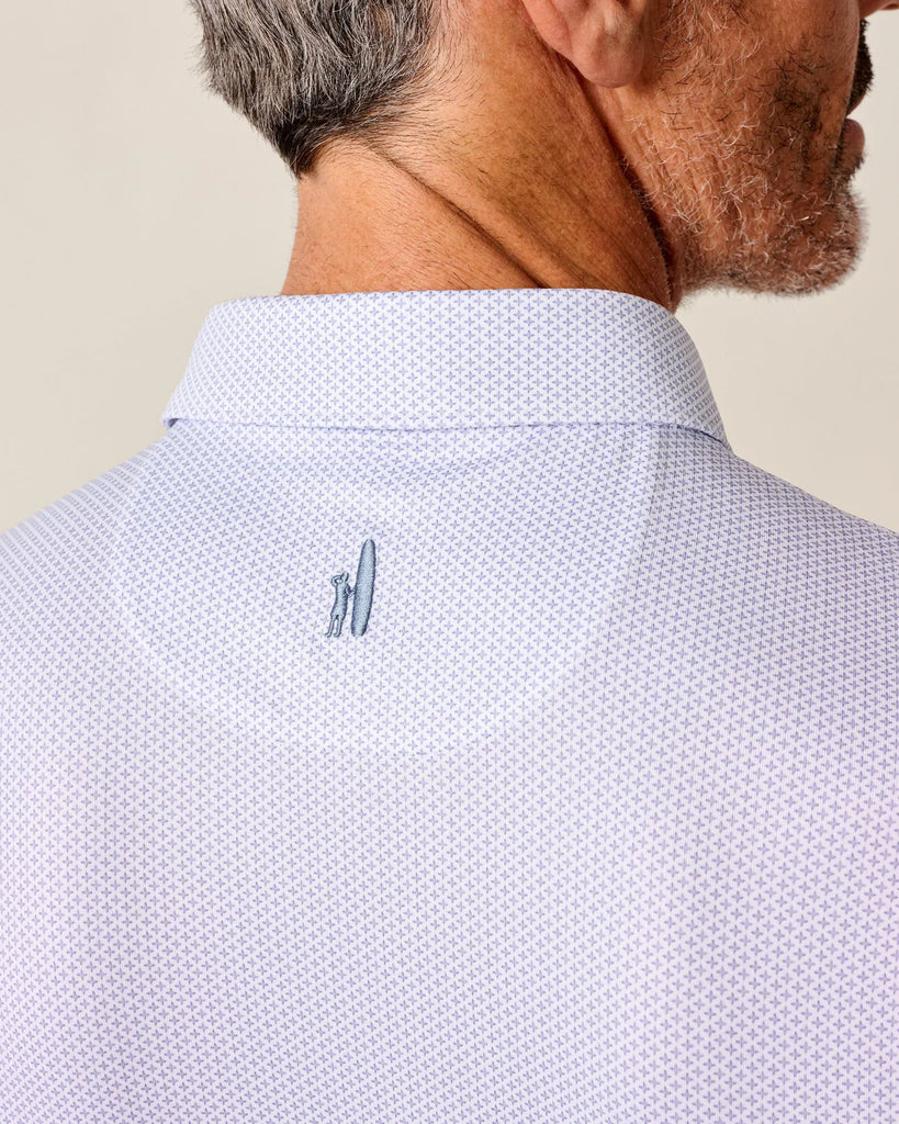 Close-up of a person wearing a light purple patterned shirt with Johnnie-O logo on a beige background