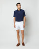 Model wearing white shorts, brown leather loafers, and navy cotton terry polo shirt with white buttons.