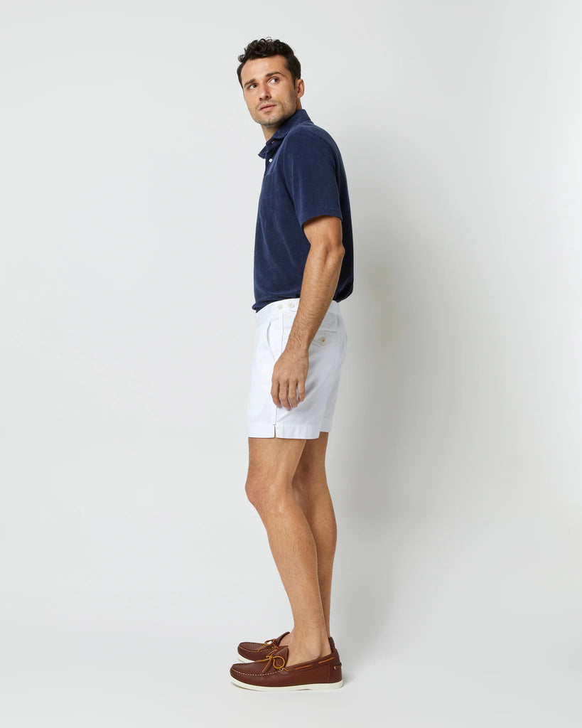 Second side view of model wearing white shorts, brown leather loafers, and navy cotton terry polo shirt with white buttons.