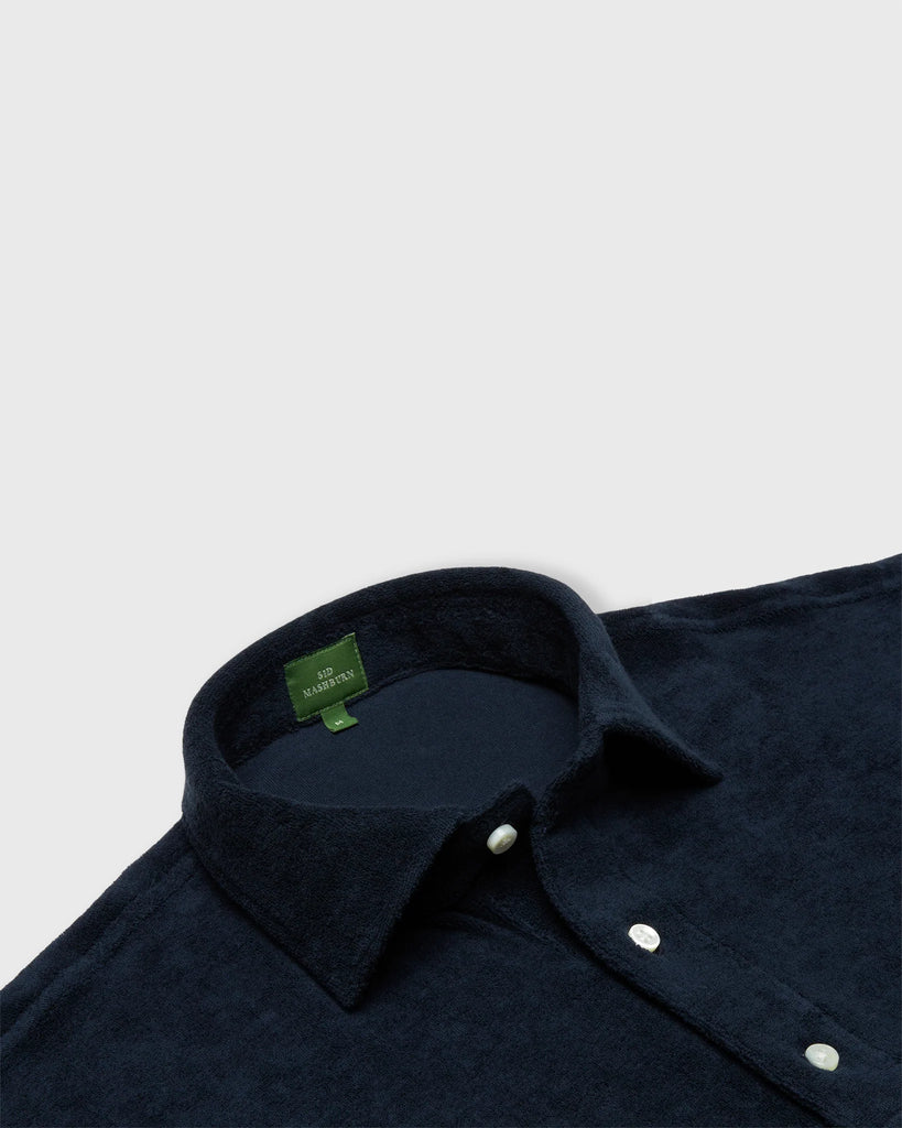 Close up shot of navy cotton terry polo shirt with white buttons.